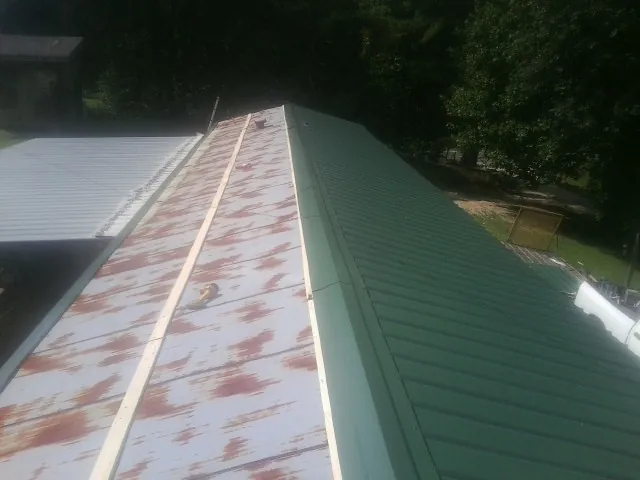 Old rusted panels beside newly installed green metal roofing — Wind Damage Roof Repair by Roofing Brothers in Mingo