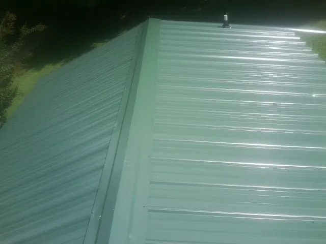 New green metal panels meeting at the ridge of a roof — Flat Roof Repair work by our crew in Mingo