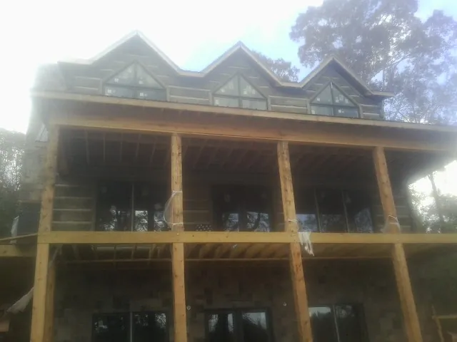 Dormers and porch framing on a large log home under construction — Roof Coating work by our crew in Mingo