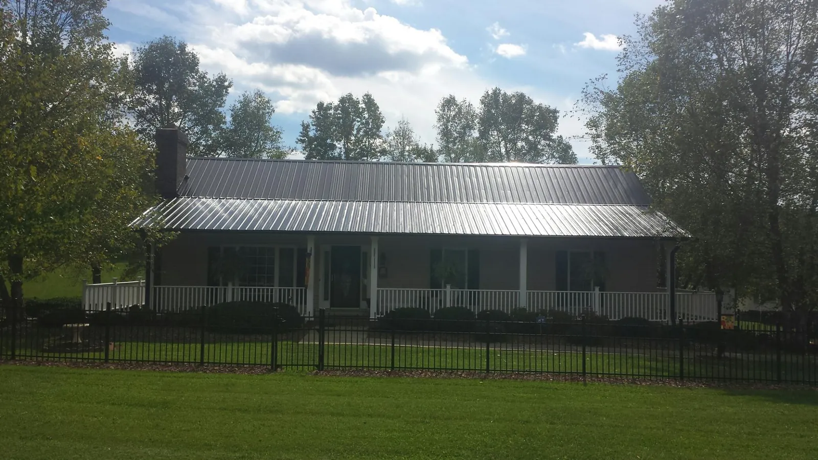 Gray metal roof on a brick ranch with a full width front porch — Gutter Guard Installation work by our crew in Mingo