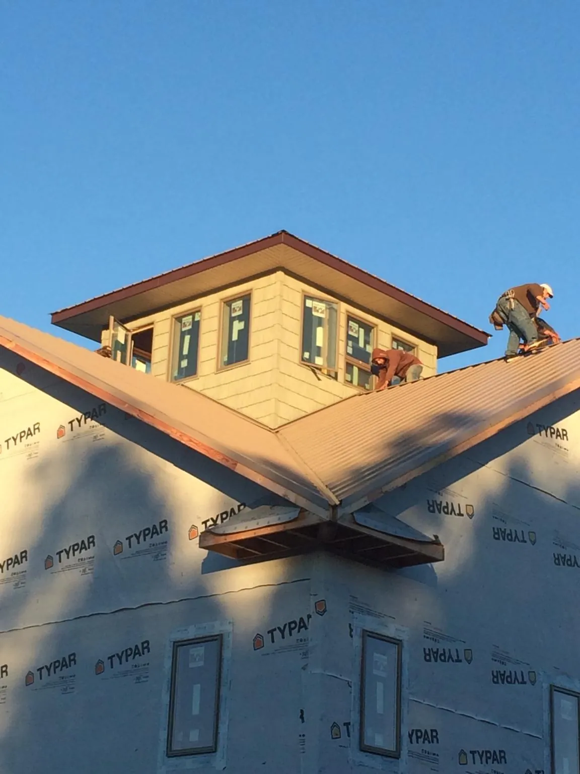 Roofers working around a rooftop cupola on a new metal roof at sunset — Roof Waterproofing in Mingo by Roofing Brothers